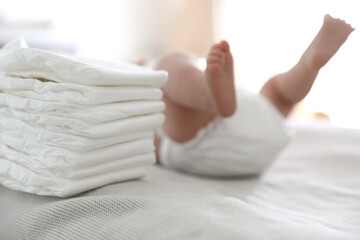 Obraz na płótnie Canvas Cute little baby in diaper lying on bed in room, closeup
