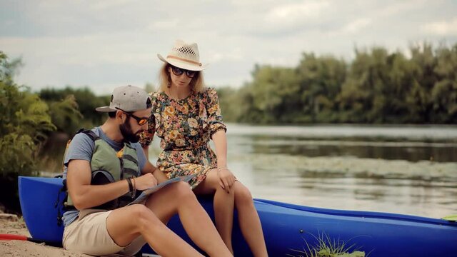 Two Tourist Traveler Sitting On Kayak.Couple Searching Way On Map On Holiday Vacation Trip.Traveling On River Holding Tourist Map For Navigate.Kayak Or Canoe Boat Rowing In Summer Weekend