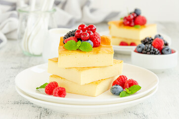 Homemade cottage cheese casserole with fresh berries and mint on top on a white plate. Healthy breakfast. Horizontal, copy space.