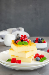 Homemade cottage cheese casserole with fresh berries and mint on top on a white plate. Healthy breakfast. Vertical, copy space.