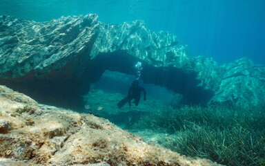 Rock formation, natural arch underwater with a man freediving in the Mediterranean sea, Catalonia, Cap de Creus, Costa Brava, Spain