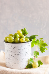 Closeup of  Fresh green gooseberries berries with leaves in a cup.