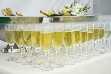 Catering on the event: sparkling wine on bottles and with glasses on the table with white cloth