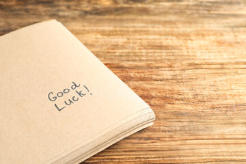 Notebook with phrase GOOD LUCK on wooden table, closeup. Space for text