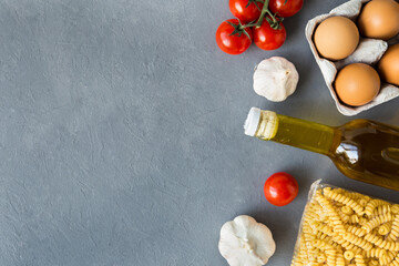 Contactless online order of goods from the store. Set of grocery items from pasta, oil, eggs, tomato. Online order of nutrition. Food delivery. Takeaway products. Flat lay, copy space, gray background