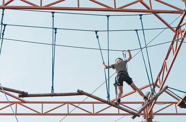 Girl on a wood rope trail in an adventure park in city outdoor activity