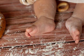 Fototapeta na wymiar small children's feet in flour on a wooden background