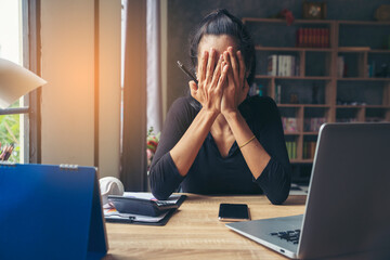 Stressed businesswoman, Frustrated, and upset in business pressure and overworked at office. Adult Asian female working on laptop, feeling tired and headache. Stressed and Frustrated concept.