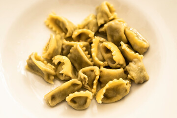plate of ravioli in white over a table of an Italian kitchen