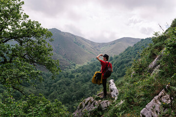 Back view female tourist doing hiking in countryside and admiring scenery of mountainous valley with english setter dog