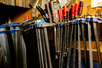 Various metal tools and clamps for woodwork placed on shelf in shabby carpentry