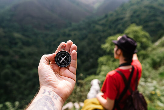 Top view of cropped unrecognizable tourist standing with compass on hand on background of mountain valley