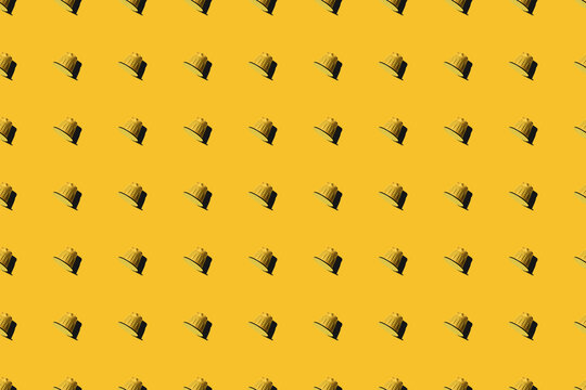 Top view of yellow coffee pods placed in even rows as seamless pattern on yellow background