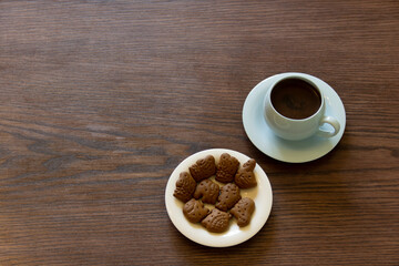 Coffee cup with chocolate cookie on dark wooden background