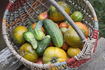 vegetables are in a basket that stands on a wooden table