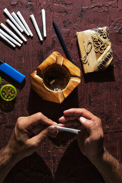 Unrecognizable male smoker making marijuana joint