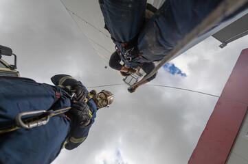 From below of rescue team of firemen standing in spacious complex and preparing for workout with ropes