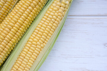 Ripe sweet corn on the cob on a white wooden background. Close-up of popular crops.