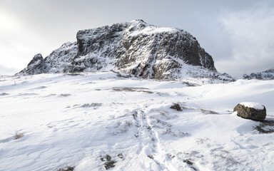 Fototapeta na wymiar Footprints in the snow towards a mountain peak in Norway. 