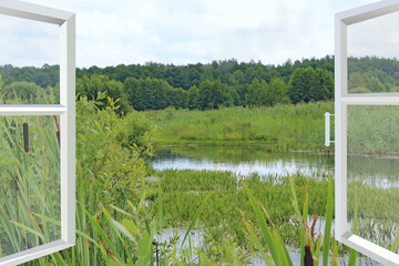 Fototapeta premium Room with wide window overlooking landscape with lake surrounded with cane