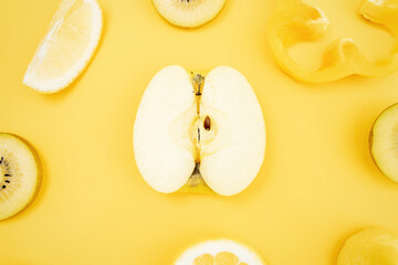 Top view of various fresh fruits and vegetables arranged on yellow background