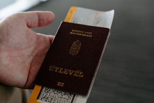 Crop unrecognizable Hungarian male traveler with national passport and boarding pass in airport waiting for flight