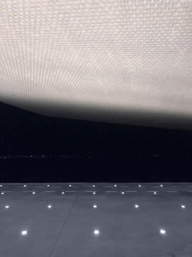 Contemporary facade of building and stone ground with glowing lamps constructed in futuristic style in evening