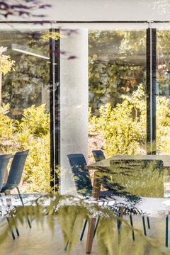 Fototapeta Modern style office interior with square tables and blue stools on floor and wooden shelves on wall with large window and lamps on ceiling