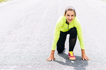 Runner woman at low start. Sportswoman girl going to run sprint outdoors