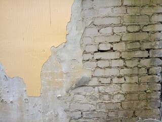 old gray brick wall with fallen plaster