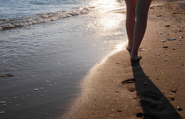 Close up female feet walking at the water's edge by the sea. footprints on wet sand, natural background,  copy space