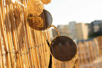 Vintage sunglasses round lens model hanging on a babmboo fence. Selective focus 
