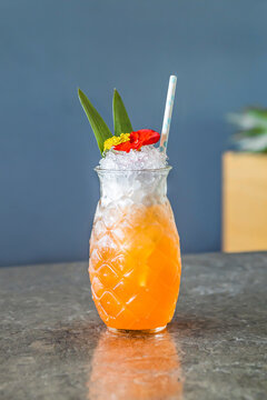 Cocktail with ice and straw in a glass in shape of pineapple