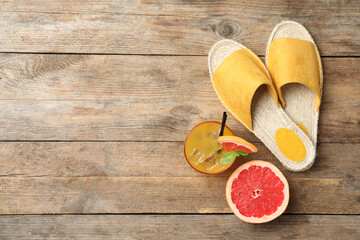 Slide shoes, cocktail, grapefruit and space for text on wooden background, flat lay. Beach objects