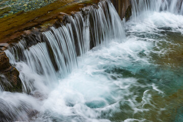 Picturesque scenery of rapid river with wide waterfall and rocky pool