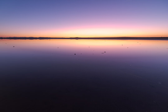 Amazing scenery of calm river with smooth water surface reflecting colorful sunset sky