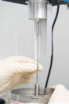 Unrecognizable scientist in gloves using viscometer while working in laboratory and conducting chemical experiment