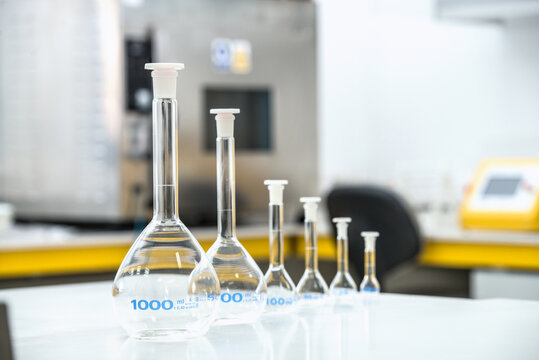 Various glass flasks placed in row on table and prepared for experiments in modern laboratory