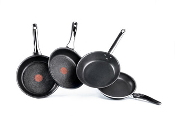 Modern frying pans with non stick coating placed in row above ground in studio