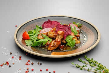 Grilled grilled meat in sauce with vegetables on a white plate.