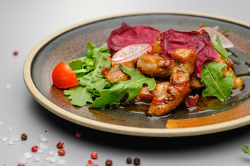 Grilled grilled meat in sauce with vegetables on a white plate.