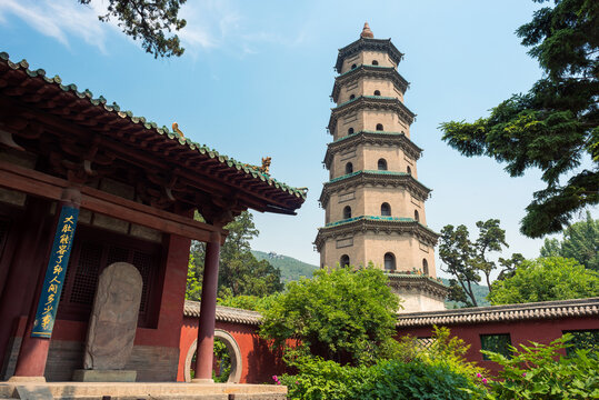 Low angle of traditional pagoda with ornamental walls surrounded by trees on background of blue sky in Shanxi