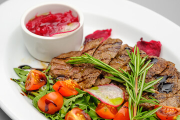 Grilled maso with vegetables and rosemary on a white plate.