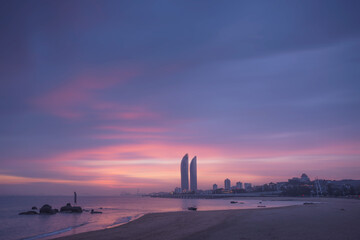 Silhouettes of contemporary skyscrapers located on seafront of Xiamen city against colorful sunset sky in evening time in China