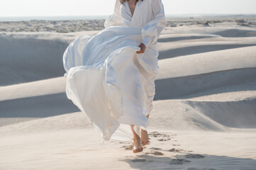 Woman running in desert in beautiful flowing bridal white dress