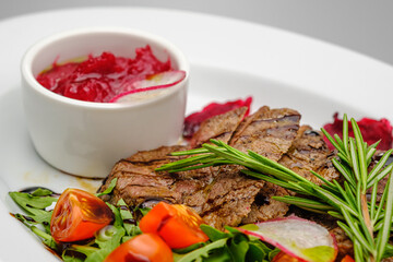 Grilled maso with vegetables and rosemary on a white plate.