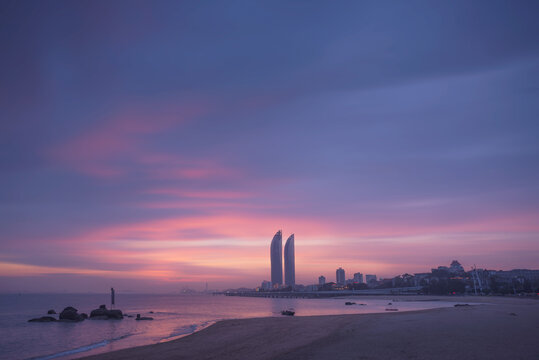 Silhouettes of contemporary skyscrapers located on seafront of Xiamen city against colorful sunset sky in evening time in China