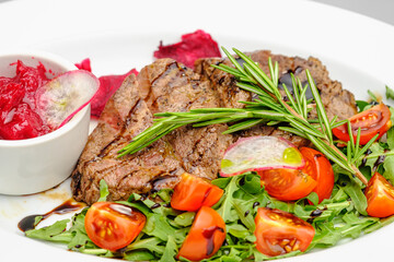Grilled maso with vegetables and rosemary on a white plate.