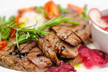 Grilled maso with vegetables and rosemary on a white plate.