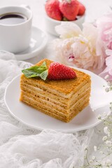 Piece honey multi layer cake, leaf mint, strawberry on plate, cup of coffee and peony. Delicate and airy composition, vertical format.